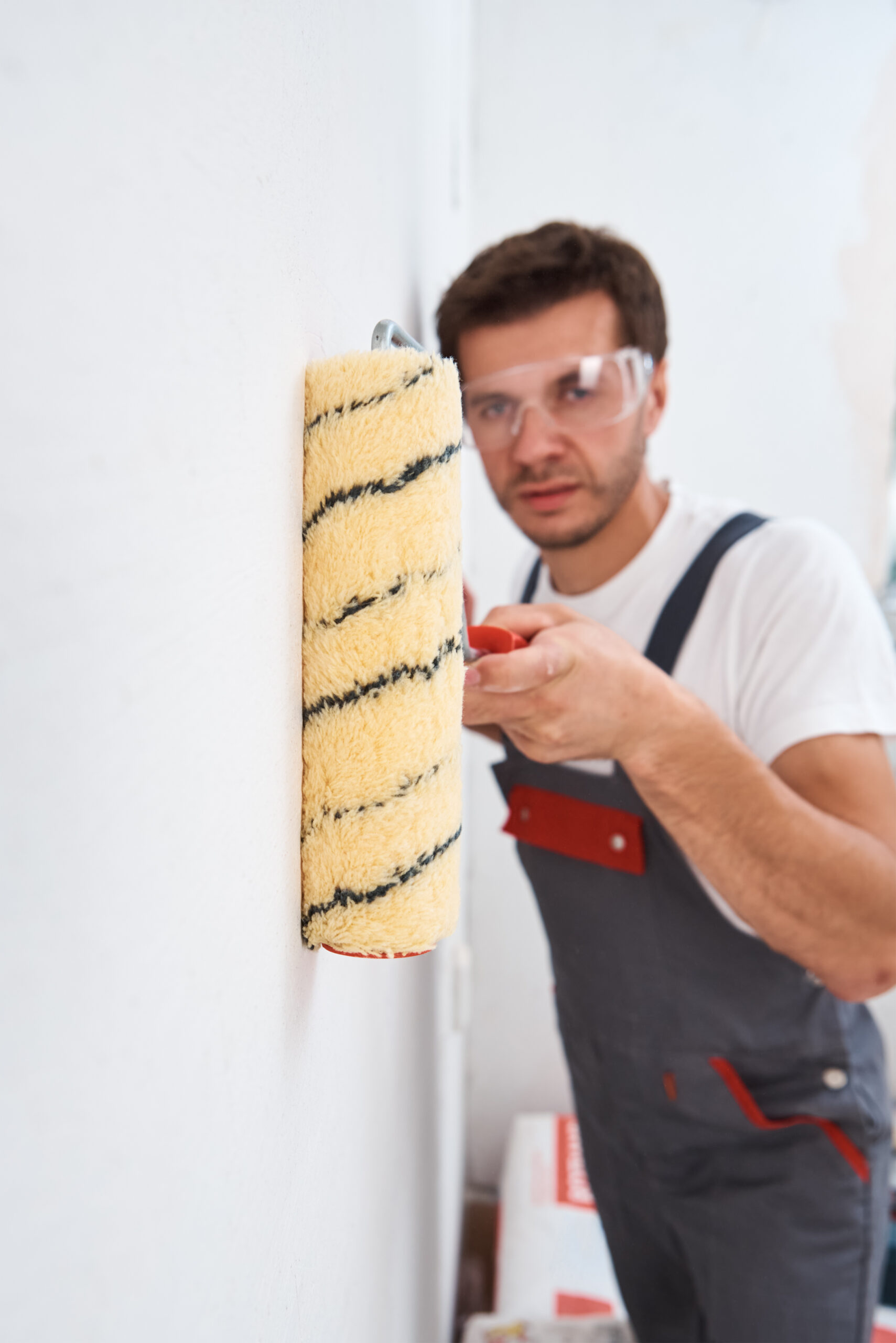 Man in uniform painting wall with paint roller. Home renovation concept